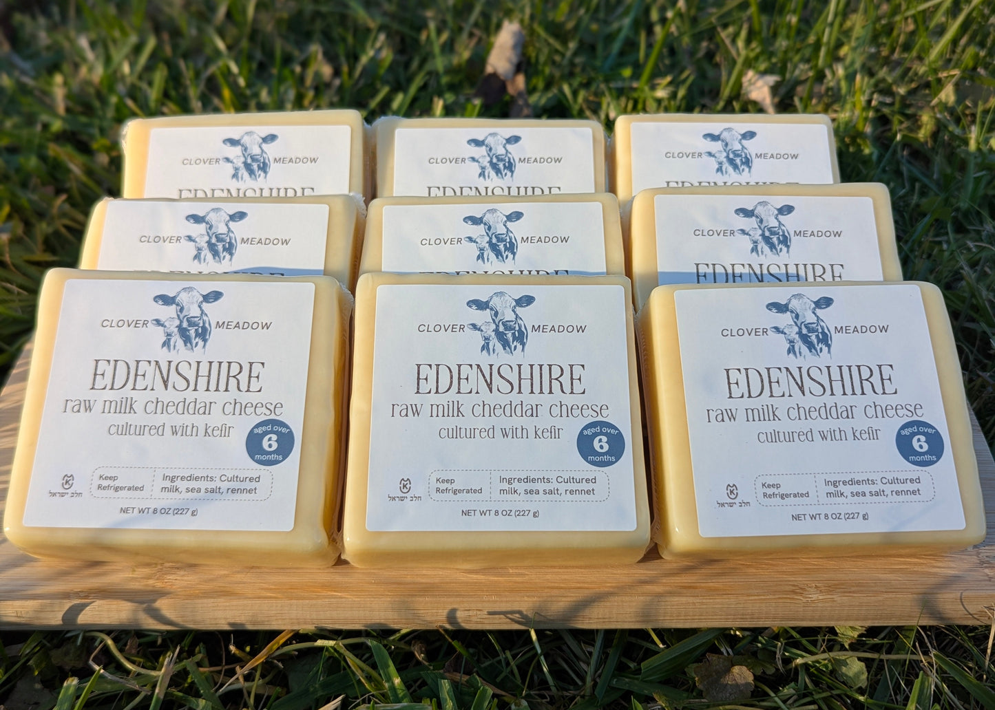 Cheese block with a label on a wooden surface and grassy background
