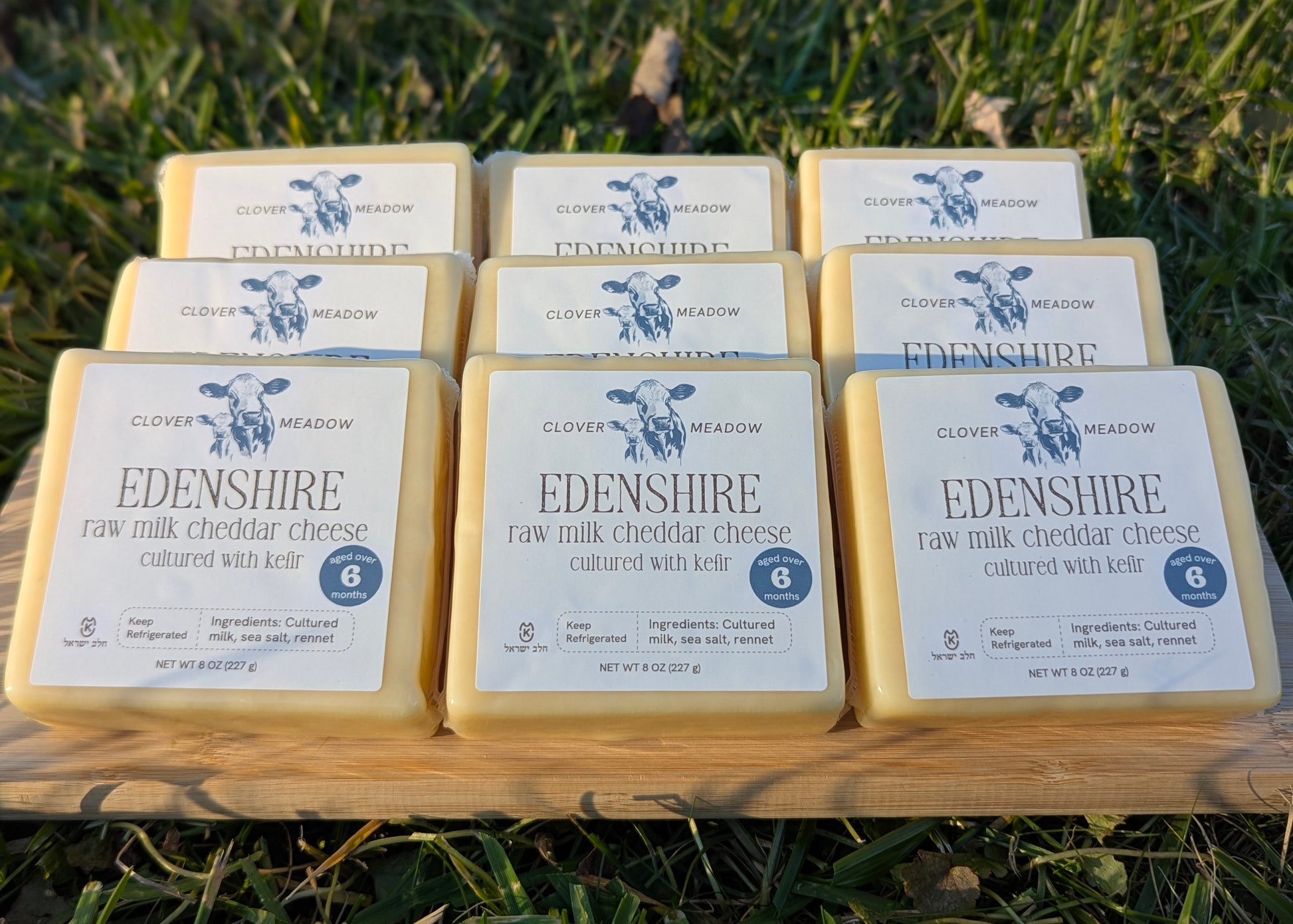 Cheese block with a label on a wooden surface and grassy background