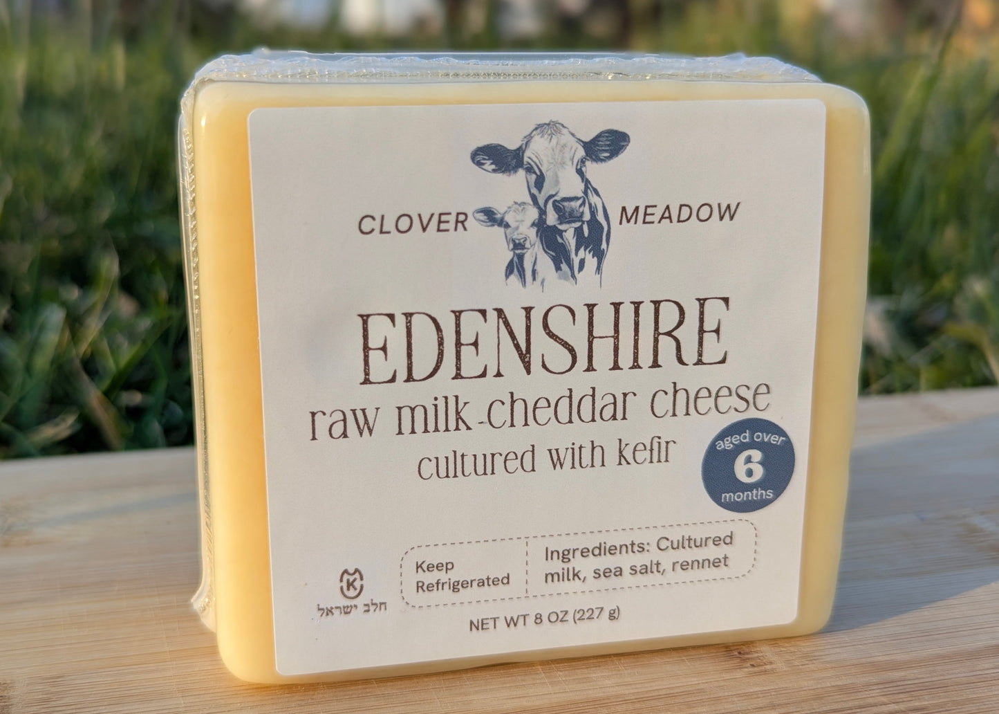 Edenshire raw milk cheddar cheese on a wooden surface with a blurred natural background